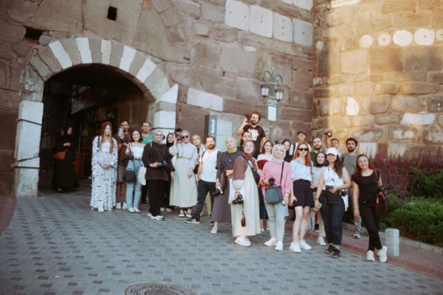 Consultant de turism care prezintă unui cuplu o ofertă de vacanță pe ecranul unui laptop, într-un birou luminos