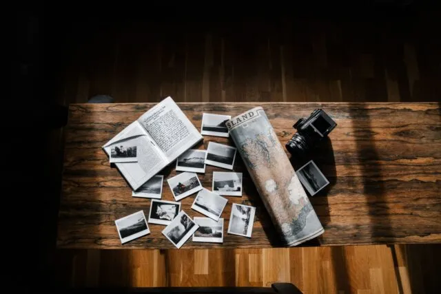 Hartă deschisă pe o masă de lemn, alături de un carnet de notițe, un pix și o cană de cafea pentru planificarea vacanței
